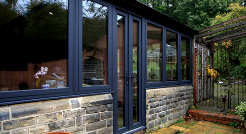 Large dark framed conservatory with dawrf stone wall